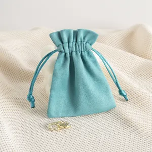 Detailaufnahme des türkisblauen Wildleder Schmuckbeutels mit Kordelzug und Perlenohrringen.