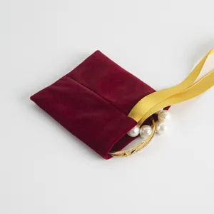 Roter Samt Geschenktasche Schmuckbeutel Detailansicht mit goldenem Armband und Perlen Verpackung.