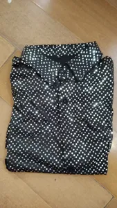 Vista dettagliata della camicia da uomo con paillettes, colletto rovesciato e pois lucidi.