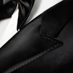 Elegante chaqueta de traje cruzada negra para hombre con solapa de satin y pajarita a juego.