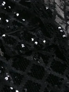 Close-up detail of black sequin fabric, showing sparkling texture and diamond pattern for men's suit.