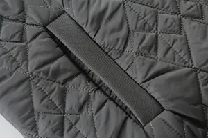 Close-up detail of dark grey quilted fabric with diamond stitching and strap accent.