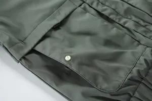Men's military green casual jacket detail shot with large pocket and metal snap button design.