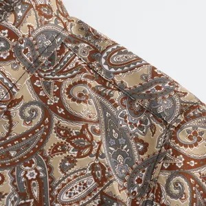 Close-up detail of men's short-sleeve paisley print shirt shoulder and collar in tan.