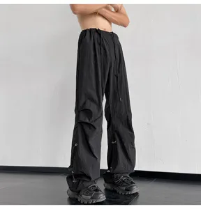 Vista detallada de pantalones paracaídas negros casuales con cordón ajustable y corte holgado.