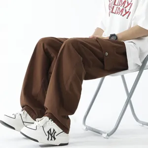 Men's brown loose cargo pants casual straight trousers worn sitting side view on chair.