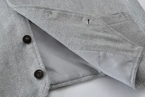 Close-up detail view of grey herringbone men suit vest showing fabric texture and lining.