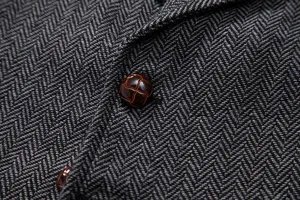 Close-up view of dark grey herringbone tweed fabric and textured button detail of mens vest.