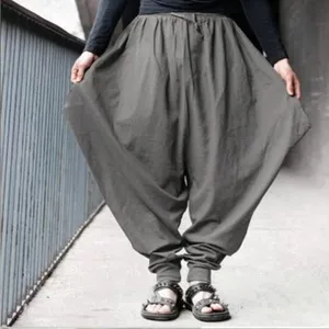 Detail shot of loose-fit drop-crotch harem pants in dark grey, featuring cuffed ankles.