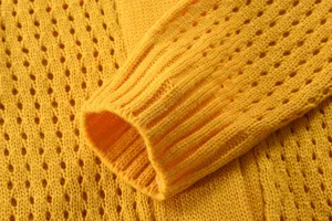 Gelber Strickpullover Detail, Lochmuster Bündchen und weicher Stoff Nahaufnahme.
