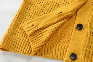 Detailaufnahme der gelben Strickjacke mit feiner Textur, Knopflöchern und schwarzen Knöpfen.