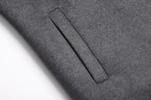 Close-up detailed view of dark gray men's wool coat pocket, featuring fine stitching craftsmanship.