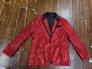 Close-up detail of the red sequin blazer featuring classic black lapel and single button.