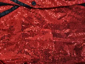 Men's red sequin blazer detail close-up view, shiny disco party jacket fabric texture.