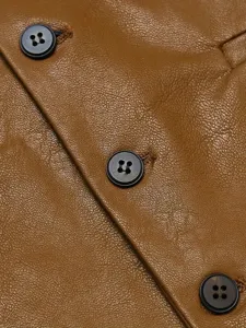 Primo piano sui dettagli del gilet in pelle marrone, texture fine e bottoni neri classici.