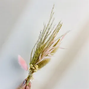 Primo piano dettagliato di un mini bouquet di fiori secchi con erba naturale e code di coniglio.