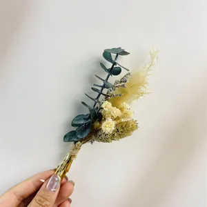 Handgehaltene Mini-Trockenblumen-Ansteckblume im Detail, ideal für Hochzeitsgäste und Trauzeugen.