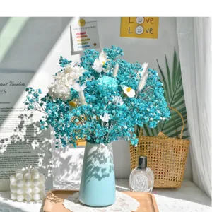 Geconserveerd blauw gipskruid bloemboeket met keramische vaas voor thuisdecoratie tafel.