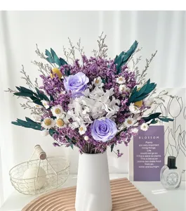 Vue détaillée du magnifique bouquet de roses et d'eucalyptus stabilisés dans un vase blanc.