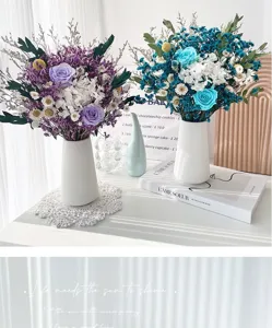 Gros plan détaillé de bouquets de roses et fleurs séchées multicolores dans des vases blancs.