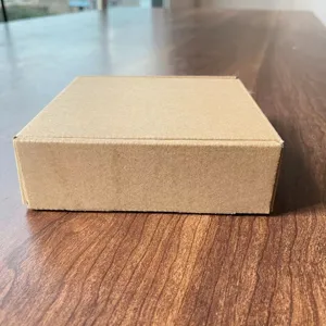 Detailansicht einer einfachen braunen Karton-Verpackung, die auf einer Holztischoberfläche liegt.