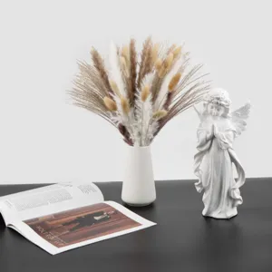 Dried pampas grass bouquet with white vase and angel statue home decor ornament.