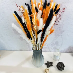 Vue détaillée d'un bouquet de fleurs séchées colorées dans un vase en verre gris moderne.