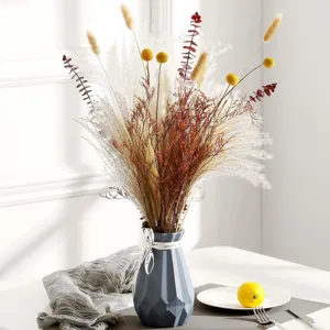 Ramo de flores secas con hierba de la pampa, bolas billy y eucalipto en un jarrón gris.