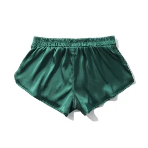 Green satin shorts detail showing silky fabric texture, elastic waistband and smooth hem.