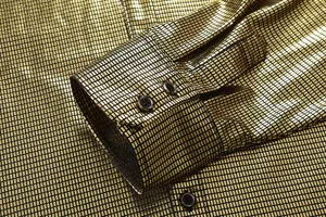 Gold metallic grid shirt cuff detail closeup, showing premium fabric texture and buttons.