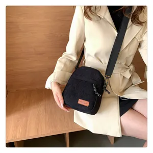 Detailed view of black corduroy crossbody bag, casual small shoulder bag with wide strap.