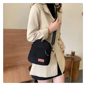 Black corduroy crossbody bag worn by model, casual messenger bag with shoulder strap.