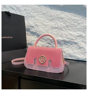 Vista dettagliata della borsa rosa con patta strutturata, manico chic e bel logo dorato.