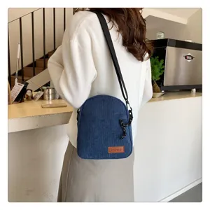 Detailed view of a blue corduroy crossbody bag with adjustable strap and textured fabric.