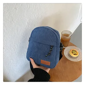 Corduroy crossbody bag detail showing the front zipper pocket and stylish fabric texture.