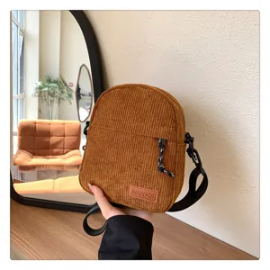 Corduroy crossbody bag detail, vintage style shoulder bag with zipper and adjustable strap.