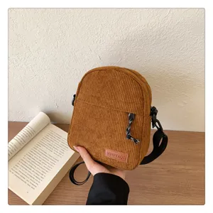Brown corduroy crossbody bag detail, featuring textured fabric, zipper closure and adjustable strap.