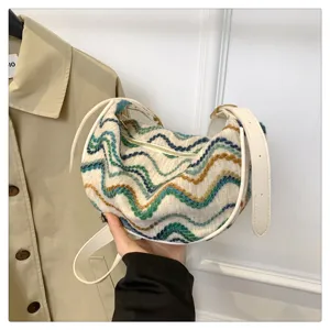 Gros plan détaillé du sac baguette élégant en tricot à motif ondulé avec sangle blanche.