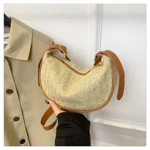 Sac bandoulière croissant en paille tissée avec bordure en cuir marron et élégant.