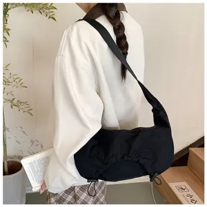 Vista dettagliata di una borsa a tracolla nera in nylon morbido indossata dal modello.