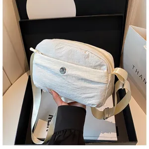 Detailed view of white nylon casual crossbody bag with front zipper pocket and metal logo.