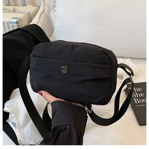 Black nylon crossbody bag with multi-layer design and metal M logo, casual daily use.