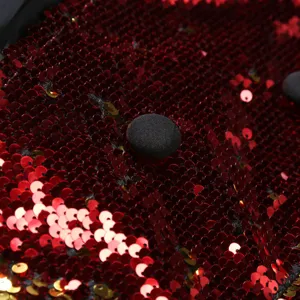 Détail de veste à sequins pour hommes avec paillettes rouges brillantes et bouton noir.