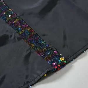 Gros plan détaillé de la bordure de sequins colorés sur tissu noir, montrant une belle finition.