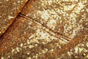 Gros plan detaille du tissu a sequins dores pour blazer de danse et costume de fete.