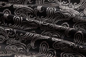 Close-up detail of black and silver paisley jacquard fabric showing rich texture and pattern.