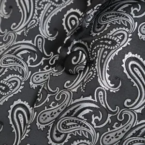 Close-up detail of mens black silver paisley jacquard suit jacket lapel and button texture.