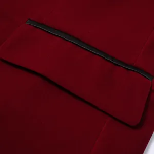 Close-up detail of men's burgundy velvet blazer pocket with black trim, premium texture style.