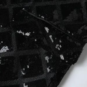 Close-up detail of black sequin men's suit jacket showing shimmering square fabric texture.
