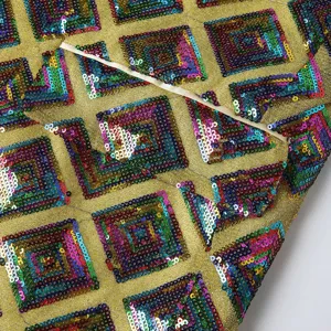 Close-up detail of men's gold sequin blazer fabric featuring vibrant multicolored geometric square patterns.